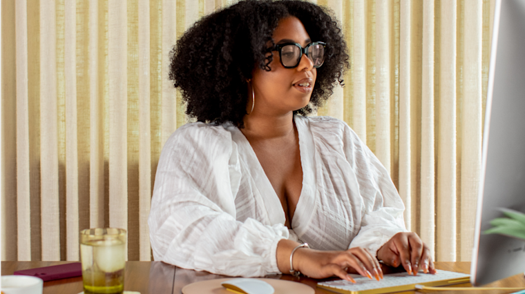 A woman in her home office, creating a CRM strategy on her computer.